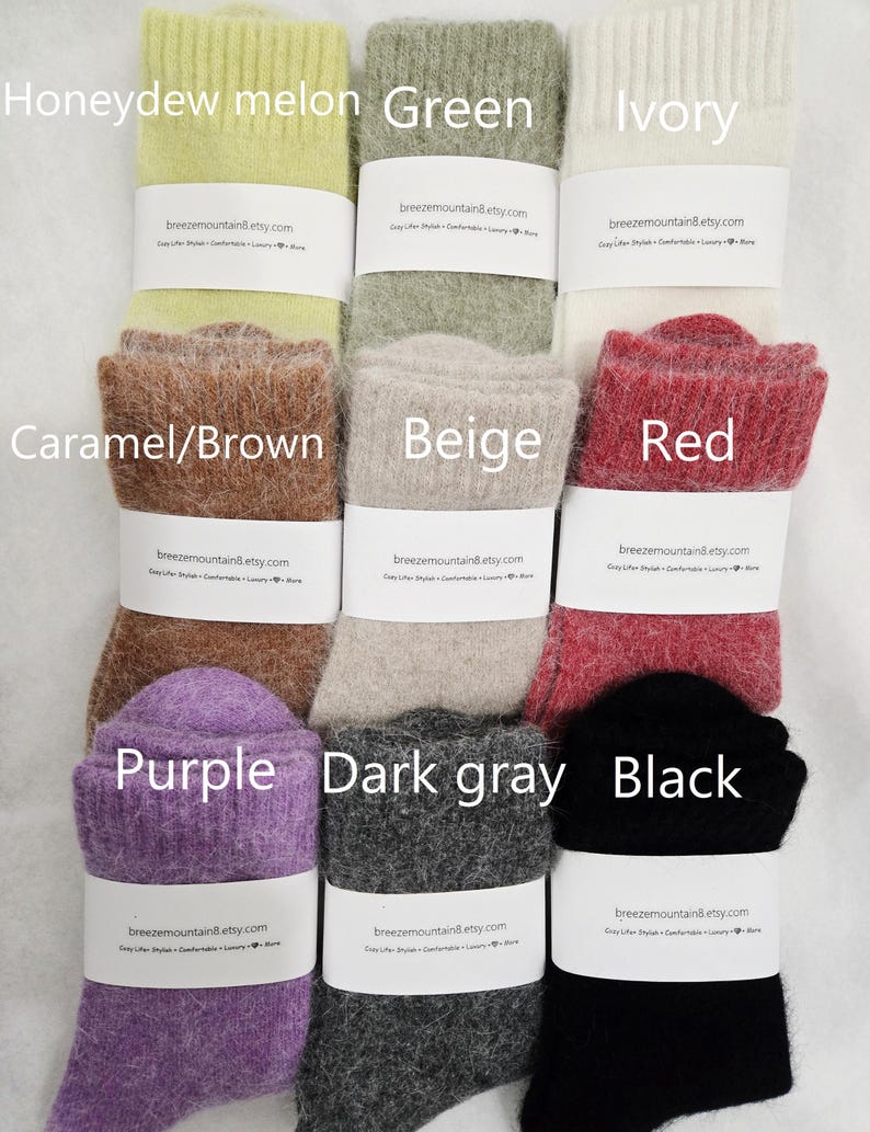 May include: A collection of nine pairs of fuzzy, ribbed knit socks arranged in a grid. The colors include honeydew melon, green, ivory, caramel brown, beige, red, purple, dark gray, and black. Each pair features a white paper band.
