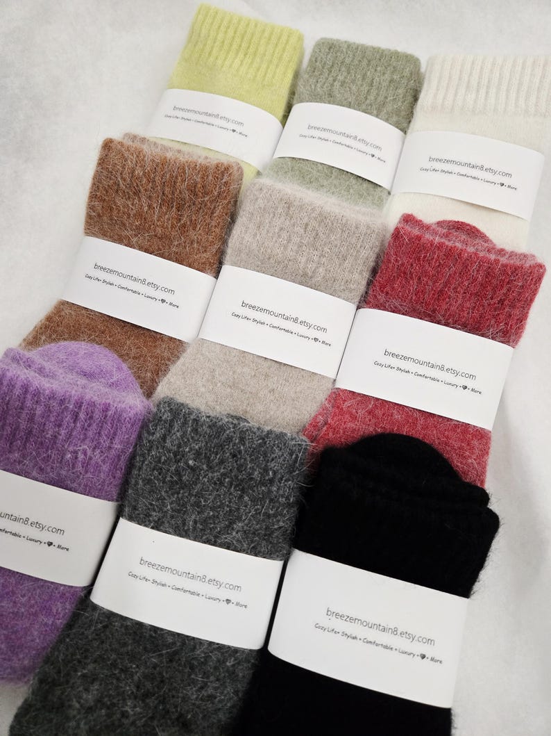 May include: A collection of nine pairs of fuzzy knit socks in various colors including lime green, sage, cream, brown, beige, red, purple, charcoal, and black. Each pair is wrapped in a white paper band labeled breezemountain8.etsy.com.