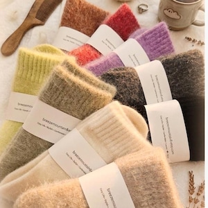May include: A collection of fuzzy, soft-textured socks in various colors including yellow, beige, cream, orange, red, purple, dark gray, and black. Each pair features a white paper band printed with the text breezemountain8.etsy.com.
