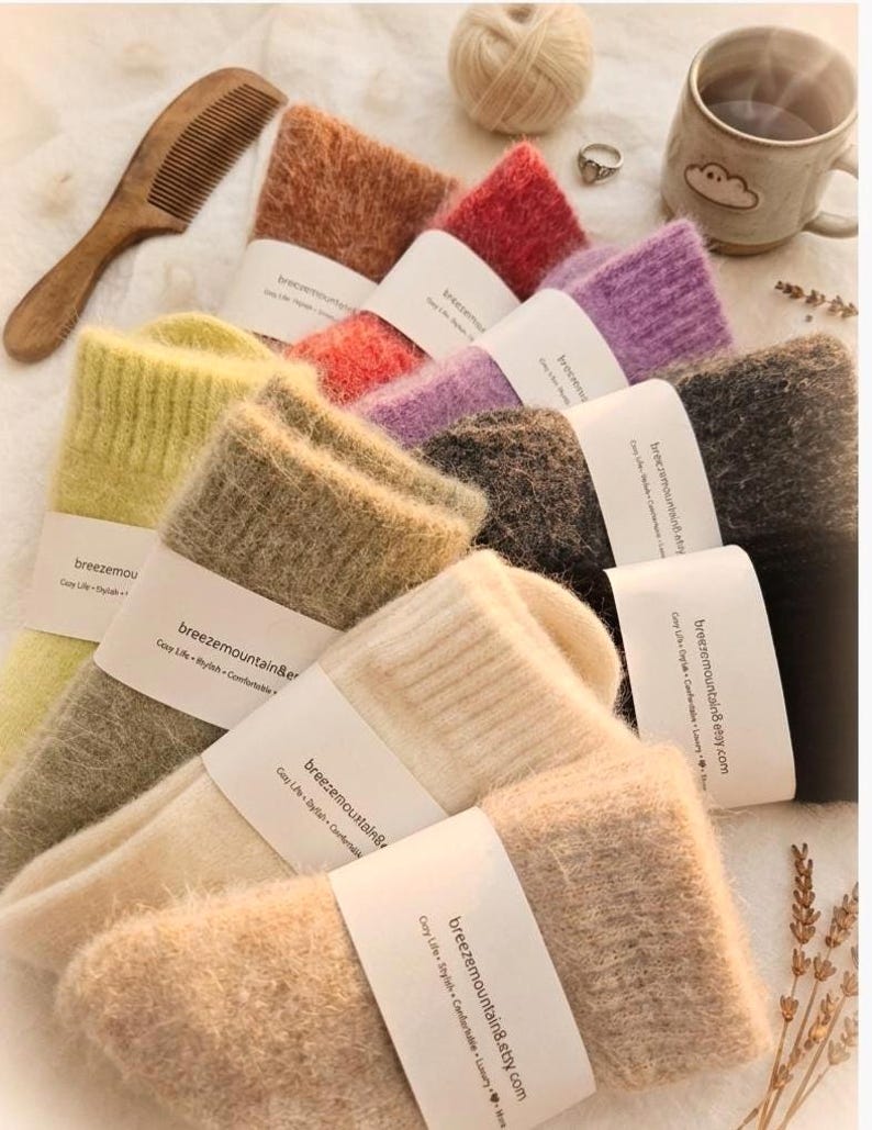 May include: A collection of fuzzy, soft-textured socks in various colors including yellow, beige, cream, orange, red, purple, dark gray, and black. Each pair features a white paper band printed with the text breezemountain8.etsy.com.
