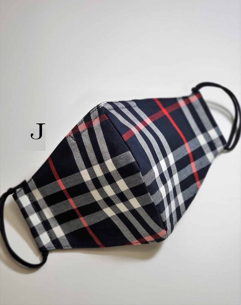 May include: A black, white, and red plaid face mask with elastic ear loops. The mask has a 'J' printed on the side.