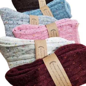 May include: Five pairs of colourful speckled socks with a ribbed texture. The socks are folded and stacked on top of each other. Each pair has a brown paper tag with the text "Thank you for making your purchase" and a website address.