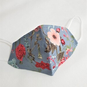 May include: A blue fabric face mask with a floral pattern featuring pink, red, and green flowers. The mask has white elastic ear loops.