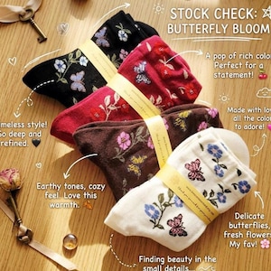 May include: A collection of five pairs of socks in various colors, including black, burgundy, brown, and cream. Each pair features a floral and butterfly design. The socks are tied together with a ribbon.