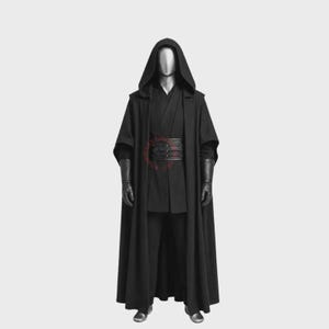 Könnte beinhalten: Ein schwarzer Kapuzenumhang über einer passenden schwarzen Tunika und Hose. Das Set enthält einen breiten schwarzen Gürtel mit horizontalen Texturdetails und lange schwarze Handschuhe. Das Outfit wird auf einer silberfarbenen Schaufensterpuppe präsentiert.