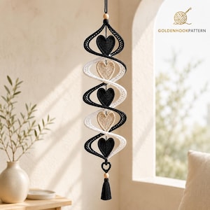 May include: A hanging spiral decoration featuring alternating black and white crocheted ribbons with three black and two beige crocheted hearts centered within the twists. The piece includes a wooden bead at the top and bottom with a black tassel.