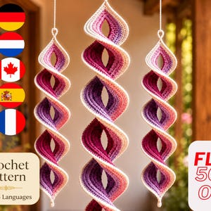 May include: Three hanging spiral decorations made of crocheted yarn in a gradient of cream, light pink, purple, and deep magenta. Each piece features a twisted, corkscrew shape suspended by a white string, showcasing a textured stitch pattern.