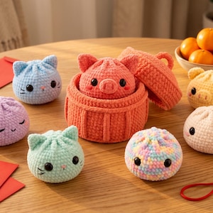 Peut inclure: Une collection de peluches crochetées en forme de brioches vapeur, incluant des motifs de chat et de cochon dans des tons pastel. Un panier vapeur central en crochet orange avec couvercle contient une peluche cochon, entouré de jouets.