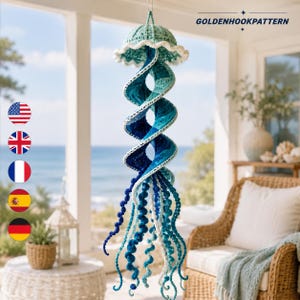 Peut inclure: Une décoration méduse en crochet suspendue avec un corps en spirale dans des tons bleu sarcelle, turquoise et bleu marine. Le sommet est un dôme vert clair avec un bord blanc volanté, et le bas présente de longs tentacules bouclés en laine.