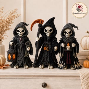 May include: Three crocheted grim reaper figures wearing black hooded robes. The left figure holds a lantern with an orange light and a key. The center figure holds a scythe and has pumpkin and moon charms. The right figure holds a lantern with a candle.