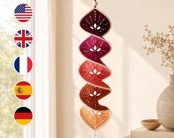 May include: A vertical hanging decoration featuring five connected crochet leaf-shaped segments in a gradient of colors from dark purple to light orange. The piece includes a wooden bead at the top, a clear crystal at the bottom, and the text GOLDENHOOKPATTERN.