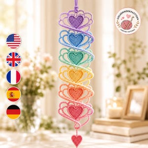 May include: A vertical hanging crochet decoration featuring six stacked heart shapes in a rainbow gradient of purple, blue, teal, yellow, orange, and pink, finished with a small pink heart at the bottom and a logo reading GOLDENHOOKPATTERN.