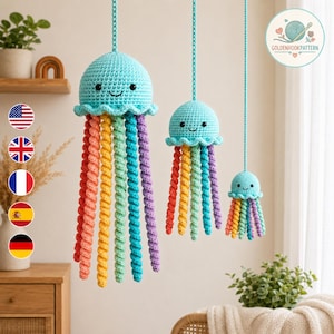 May include: Three hanging crochet jellyfish ornaments in descending sizes, each featuring a light blue rounded head with black eyes and a smiling mouth, and multiple spiral tentacles in shades of red, orange, yellow, green, and purple.