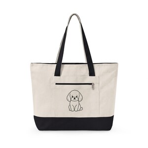Può includere: Una borsa tote in tela color crema con un grafico di barboncino ricamato in nero sulla tasca anteriore. La borsa ha una base nera solida e due lunghi manici neri. Una tasca orizzontale con cerniera si trova sopra il disegno del barboncino.