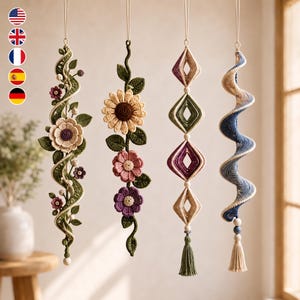 May include: Four hanging crochet ornaments. The first is a green vine with cream and purple flowers. The second features a large sunflower and two smaller pink and purple flowers. The third has four diamond shapes in cream and purple. The fourth is a blue and cream spiral with a tassel.