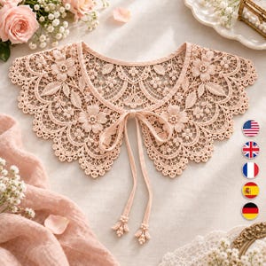 Puede incluir: Un cuello de encaje en color melocotón claro con un intrincado patrón floral y bordes festoneados. El cuello tiene un escote redondeado y dos lazos largos y finos de tela a juego en la parte delantera, terminados con pequeñas borlas de cuentas.