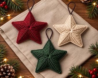 May include: Three star-shaped ornaments crafted from yarn, featuring one deep red, one cream, and one dark green star. Each star has a textured, ribbed surface and a thin brown loop attached to the top point for hanging, arranged in a triangular formation.