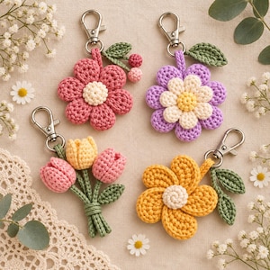 Pode incluir: Quatro porta-chaves de flores em croché com fechos mosquetão prateados. Um apresenta uma flor rosa com centro creme e bagas, outro uma flor roxa com centro creme, um ramo de três túlipas e uma flor amarela com centro creme.