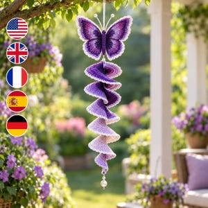 May include: A crocheted hanging ornament featuring a purple butterfly at the top with white-tipped wings, connected to a long, spiraling, ombre-colored tail that transitions from deep purple to light lavender, finished with a white bead at the bottom.
