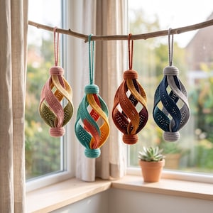 Pode incluir: Quatro ornamentos de croch&ecirc; pendurados em um galho de madeira. Cada ornamento apresenta um design esf&eacute;rico vazado com tiras de tecido torcidas e multicoloridas em tons de rosa, verde, azul-petr&oacute;leo, laranja, vermelho escuro, azul marinho e cinza.