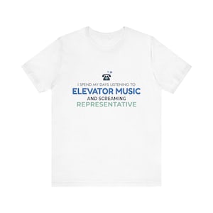 Op de afbeelding: Een wit t-shirt met korte mouwen voorzien van een afbeelding van een zwart telefoonicoon en de tekst I SPEND MY DAYS LISTENING TO ELEVATOR MUSIC AND SCREAMING REPRESENTATIVE in blauwe, donkergrijze en lichtgroene letters op de borst.