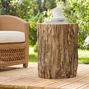 May include: A cylindrical side table crafted from a natural tree trunk with visible rough, textured bark. The top surface is flat and supports a stack of two white ceramic cups and a small white plate, creating a rustic and functional outdoor piece.
