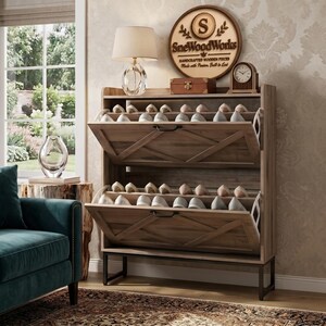 May include: A light brown wooden shoe cabinet featuring two tilt-out storage compartments with X-shaped decorative accents on the front panels. The unit is supported by a black metal frame and contains multiple pairs of shoes on internal shelves.