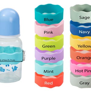 Pu&ograve; includere: Un biberon trasparente con tappo azzurro e una fascia in silicone turchese, accanto a due pile verticali di fasce in silicone colorate etichettate Blue, Pink, Green, Purple, Mint, Red, Sage, Navy, Yellow, Orange, Hot Pink e Gray. La fascia misura 2,5 cm per 5,7 cm.