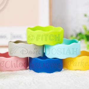 Pu&ograve; includere: Una collezione di sei braccialetti in silicone ondulati nei colori verde lime, grigio, azzurro, rosa, blu scuro e giallo. Ogni braccialetto &egrave; inciso con un nome e una piccola icona, tra cui FITCH, DANIEL, JOSIAH, CHLOE, GLADYS e PARKER.