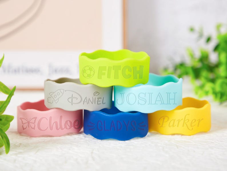 Pu&ograve; includere: Una collezione di sei braccialetti in silicone ondulati nei colori verde lime, grigio, azzurro, rosa, blu scuro e giallo. Ogni braccialetto &egrave; inciso con un nome e una piccola icona, tra cui FITCH, DANIEL, JOSIAH, CHLOE, GLADYS e PARKER.