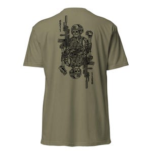 May include: An olive green t-shirt featuring a black graphic print on the back. The design depicts two mirrored skull figures in tactical gear, each holding a rifle and a grenade. The text 0311 is printed vertically on both sides of the graphic.