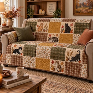 May include: A sofa cover featuring a patchwork design with alternating squares of autumn-themed patterns, including cats, maple leaves, acorns, and plaid prints in shades of brown, green, and gold. The quilted fabric has a textured finish.