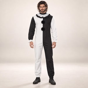May include: A long-sleeved jumpsuit featuring a split black and white color-blocked design. The garment includes a ruffled collar, gathered cuffs at the wrists and ankles, and two large black pom-poms centered vertically on the front torso.