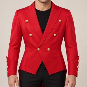 Könnte beinhalten: Ein leuchtend roter zweireihiger Blazer mit spitzem Revers, langen Ärmeln mit jeweils drei goldfarbenen Knöpfen an den Manschetten und sechs markanten goldfarbenen Knöpfen auf der Vorderseite. Die Jacke wird über einem schwarzen Shirt getragen.