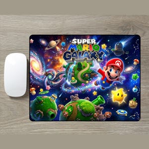 Puede incluir: Una alfombrilla de ratón rectangular con el logotipo del videojuego Super Mario Galaxy, Mario flotando en el espacio y varios planetoides verdes con setas, estrellas y tuberías sobre un fondo vibrante y colorido de nebulosa espacial.