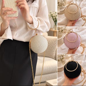 May include: A spherical clutch bag with a textured surface, available in beige, lavender, and black. The bag features a gold-toned circular metal handle, a matching gold-toned chain shoulder strap, and a secure metal clasp closure at the top.