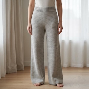 May include: Light gray knit trousers featuring a wide-leg silhouette and a high-rise waistband with a ribbed texture. The pants are crafted from a textured yarn with a consistent stitch pattern throughout, extending down to the ankle-length hem.