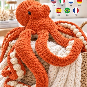 Puede incluir: Un peluche de pulpo grande tejido a ganchillo con un exterior naranja vibrante y una parte inferior de color crema con ventosas redondeadas y texturizadas. El pulpo tiene dos ojos oscuros y redondos y ocho tentáculos largos y flexibles.