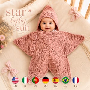 Puede incluir: Un saco de dormir para bebé de ganchillo en color rosa empolvado con forma de estrella de cinco puntas, capucha puntiaguda y dos botones circulares en la parte delantera. El texto "star byby suit" aparece en la esquina superior izquierda.