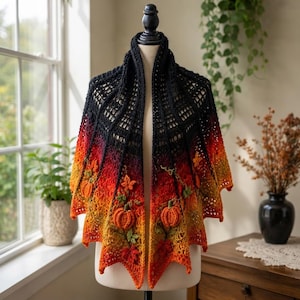 May include: A triangular crochet shawl featuring a gradient colour transition from black at the top to orange, yellow, and red at the bottom. The shawl is decorated with three-dimensional crocheted pumpkins and autumn leaves in orange and green.