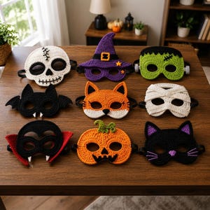 May include: A collection of nine crocheted Halloween masks featuring a white skull, a purple witch hat, a green monster, a black bat, an orange fox, a white mummy, a black vampire with red collar, an orange jack-o'-lantern, and a black cat.