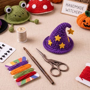 May include: A purple crocheted wizard hat with yellow star appliques, a wooden crochet hook, metal stork scissors, a spool of thread, a card of colorful embroidery floss, black safety eyes, and crocheted figures including a frog and pumpkin.