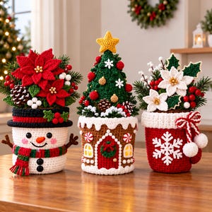 Könnte beinhalten: Drei gehäkelte Weihnachtsdekorationen bestehend aus einem Schneemann-Topf mit roten Weihnachtssternen, einem Lebkuchenhaus-Topf mit grünem Weihnachtsbaum und einem roten Tassen-Topf mit weißen Weihnachtssternen, verziert mit Beeren und Tannenzweigen.