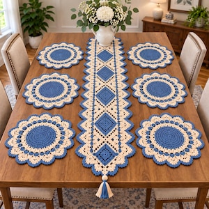 Può includere: Un set di sei tovagliette rotonde all'uncinetto e un lungo runner da tavola rettangolare all'uncinetto. Gli articoli presentano un design bicolore con un centro blu profondo e un bordo smerlato color crema. Il runner include una nappa decorativa.
