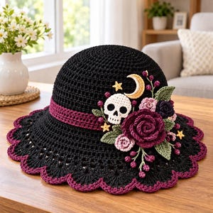 Peut inclure: Un chapeau crocheté noir avec une bande bordeaux foncé et un bord festonné. Le chapeau est orné d'un crâne blanc, d'un croissant de lune doré, de petites étoiles jaunes, de feuilles vertes et de roses crochetées en nuances de bordeaux.