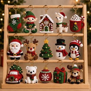 Pode incluir: Uma coleção de quinze enfeites de Natal em crochê pendurados num expositor de madeira. Os ornamentos incluem uma meia, um elfo, uma casa de gengibre, uma lhama, uma caneca de cacau, o Pai Natal, uma rena, uma árvore, um boneco de neve, um pinguim, um camião, um urso, uma bola, um presente e um veado.