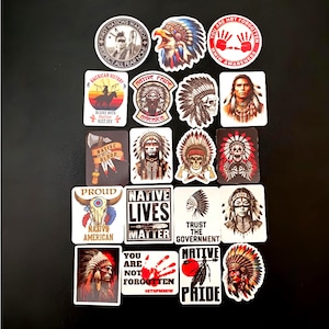 May include: A collection of twenty stickers featuring diverse Native American-themed imagery, including portraits of individuals in traditional headdresses, skulls, animal skulls, and text-based designs like Native Lives Matter and MMIW Awareness.