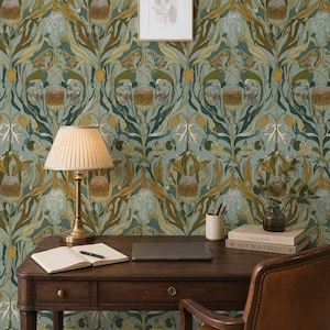 May include: A dark wood desk with a drawer, a pleated beige lampshade on a brass lamp, an open notebook with a pen, a closed laptop, a cylindrical pen holder, and a stack of books titled This is Home and Live Beautifully against floral wallpaper.