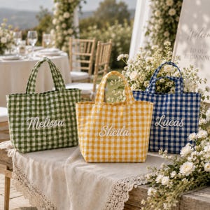 May include: Three tote bags with a gingham pattern in green, yellow, and blue. Each bag features two handles and white embroidered names on the front: Melissa on the green bag, Sheila on the yellow bag, and Lucas on the blue bag.