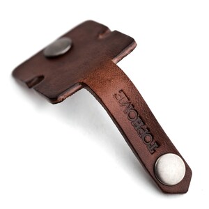 May include: Brown leather key holder with a metal loop and the word "TOPHOME" embossed on the strap.